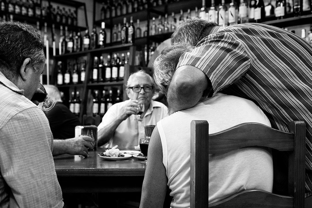 Several people talking beside a bar counter.